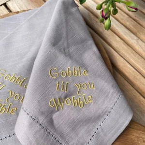 Servett i bomull med broderad text Gobble til you wobble, Grå, sälj two-unit