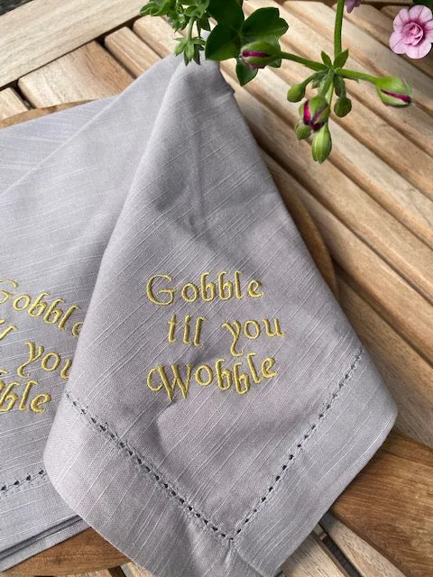Servett i bomull med broderad text Gobble til you wobble, Grå, sälj two-unit